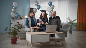 family with their graduate daughter holding diploma celebrate graduation from university at home with balloons in the background