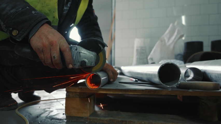 Male locksmith working in production. A man cuts a metal pipe with his hand without protection. Sparks flying off cutting a metal pipe. | Shutterstock HD Video #1070992864
