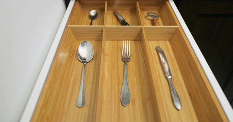 One piece of every type of cutlery put neatly in the drawer of the kitchen cabined as a minimalist organizing system