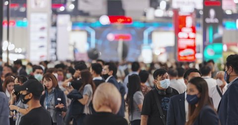 Bangkok, Thailand - Mar 24, 2021: Crowd of Asian people walk in exhibition show convention center, wear face mask. Business tradeshow event, commercial marketing activity concept