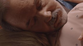 The bearded old man hugs his wife lovingly, they remain so. Hugging concept. Close up.Video for the vertical story.