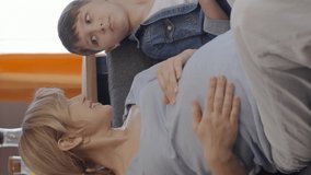 A little boy loves his pregnant mother's tummy and chats.Little boy touching abdomen of his pregnant mother. Mother child, brotherly love.Video for the vertical story.