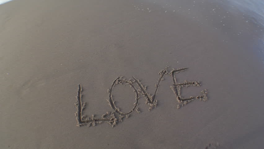 The word love is written in the sand and a wave comes to wash it away.