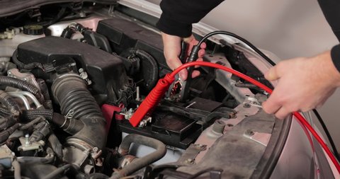 Attaching booster cable to a discharged car starter battery to jump start vehicle