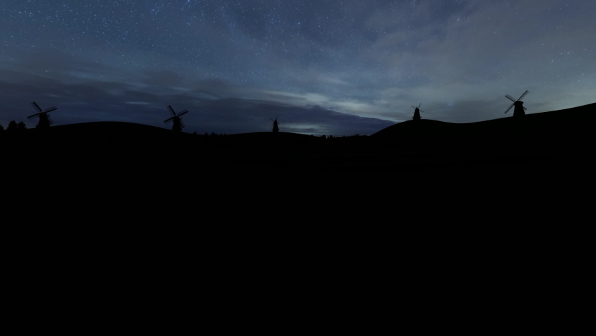 Windmill in silhouettes on a hill during nighttime