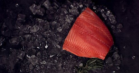 SUPER SLOW MOTION Overhead view of fresh uncooked salmon fillet falling onto ice pile. Shot with high speed camera, 420 FPS