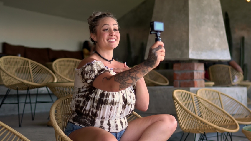 Pretty Caucasian woman shooting video vlog via modern GO PRO camera using monopod during streams session, cheerful hipster girl in casual wear talking for making selfie content on leisure Royalty-Free Stock Footage #1071010975