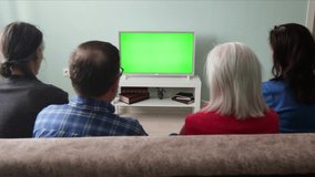 Family watching TV. Green screen.
A family of four is sitting on the couch at home. In front of them is a green screen TV. 