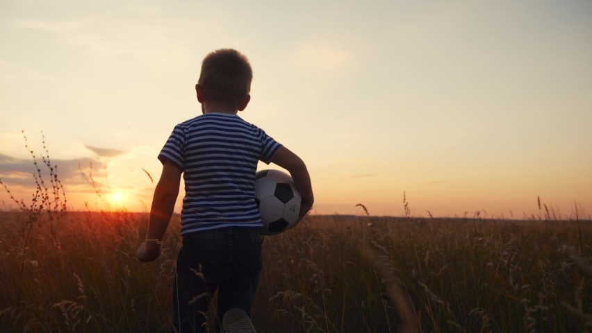 Childhood dream. boy holding soccer ball run in the park silhouette. happy family kid dream concept. kid boy run on the field silhouette at sunset carries a soccer ball fun. baby winner Royalty-Free Stock Footage #1071011971