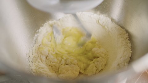 Top-view close up of working professional stand mixer making dough in bowl at kitchen