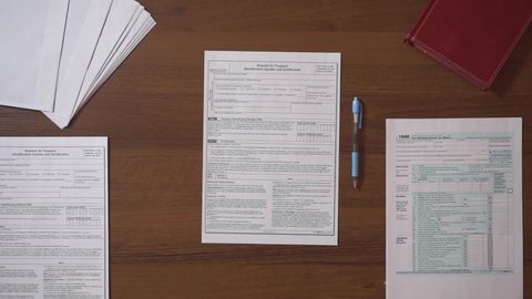 Man filling in Individual income tax return at table. Overhead view of hand filling up tax form. Income tax return deduction refund concept