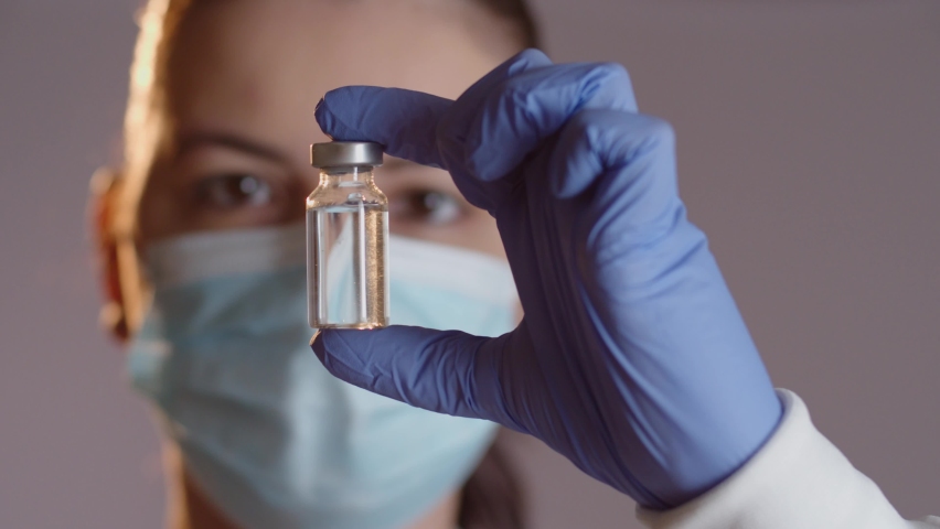 Female doctor or scientist looking at and examining vaccine vial Royalty-Free Stock Footage #1071016411