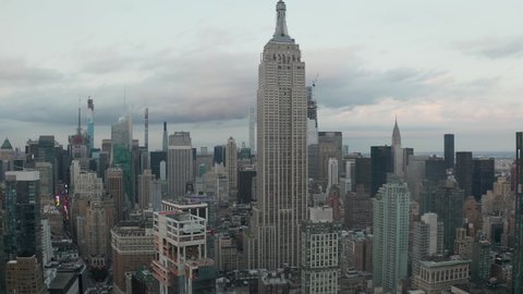 Ascending pedestal aerial view of Empire State Building drone shot surrounded by tall skyscrapers in the New York City skyline, Manhattan Circa September 2019