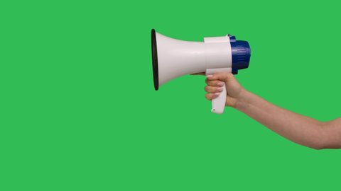 Megaphone close up rised in female hand on green screen chroma key background. White loudspeaker for social performance in raised hand. Special announcement, advertisement or broadcast. Slow motion.