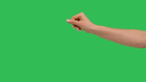 Close up side view of beautiful outstretched female hand with a sprinkling gesture isolated on green screen chroma key background. Chef hand adds pinch salt or spice to the dish. Slow motion.