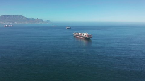 A large container ship for transporting goods near the port of Capetown, South Africa. A container ship carries cargo across the ocean. Transportation. Delivery. Logistics. Aerial 4K shot.