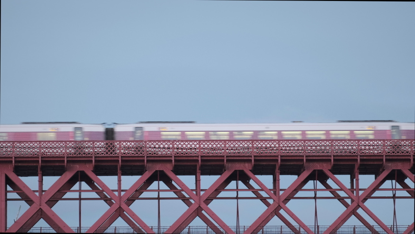4K Video of a train is moving along an old Victorian railway bridge over the sea against the blue sky. Forth Railway Bridge, South Queensferry, Scotland, United Kingdom