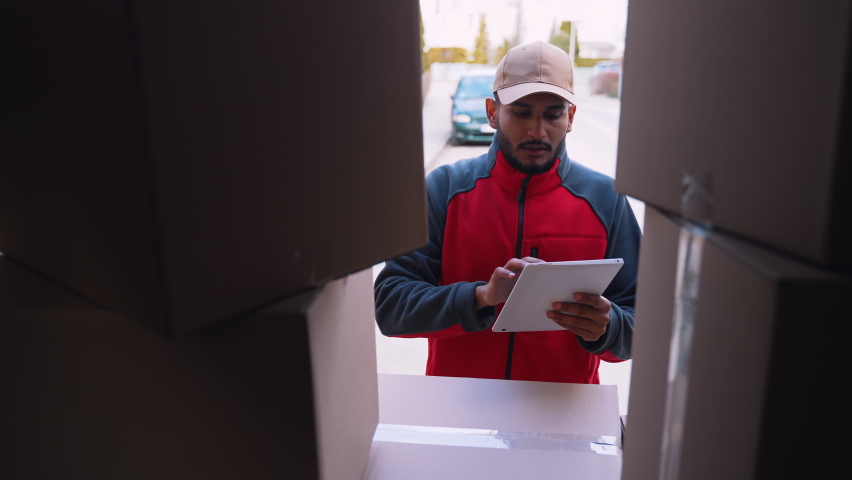 Young indian man courier using tablet while delivering parcel. High quality 4k footage | Shutterstock HD Video #1071026002