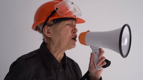 Portrait of an elderly woman architect with a megaphone and in a protective helmet. Shouts into the loudspeaker - Powered by Shutterstock - Get 15% off with code: PIKWIZARD15