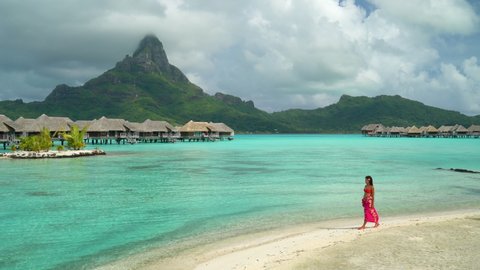 Bora Bora luxury hotel vacation tourist woman relaxing by ocean beach with view of Mt Otemanu in Tahiti, French Polynesia. High End resort with overwater bungalows villas