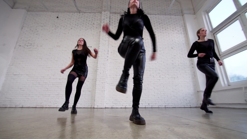 View from below of three attractive women in black costumes performing modern shuffle dance in the studio Royalty-Free Stock Footage #1071031333