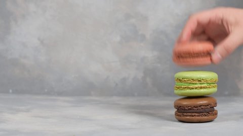 Boy lays out three macaroons to take a photo on grey background. Macaroons on grey background, colorful french cookies macaroons. Creative layout made of colorful macaroons.