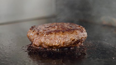 Cooking beef or pork patty for burger. Meat roasted at kitchen grill.