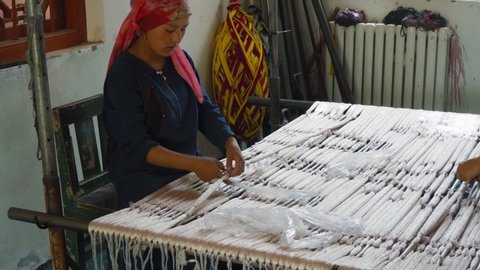 Khotan , China - 06 01 2016: Uyghur woman preparing the silk pattern before dying the silk threads with natural colors in Khotan, Xinjiang, China