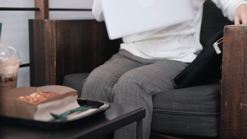 Woman opening laptop working at coffee shop enjoying eating and drinking.