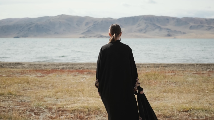 girl in goes to lake against sky,against mountains sunny weather