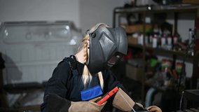 Video of a young pretty woman welder working in the garage