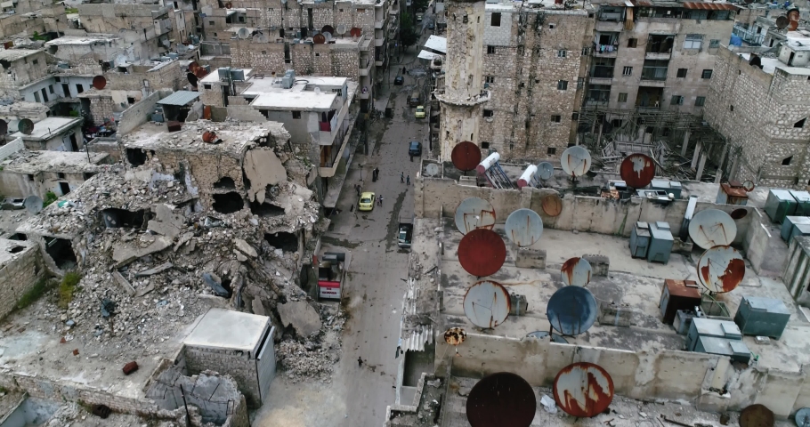 A syrian city with people in a street walking. Some of the buildings are still in ruins after the civil war 10 years ago - aerial view with a drone 4K
