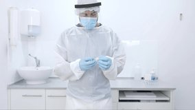 Crop focused professional male medical practitioner in surgeon gown gloves and face shield filling syringe with medication from vial while working in modern equipped hospital