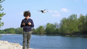 6 year old boy make shooting video and pictures  with drone in nature near a river - new technology about video 4k and photography 
