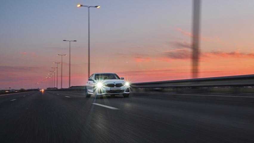 Berlin, Germany- 10.04.2021: Rolling shot of a BMW 3 series, luxury sport sedan car driving on highway at sunset, close up view 