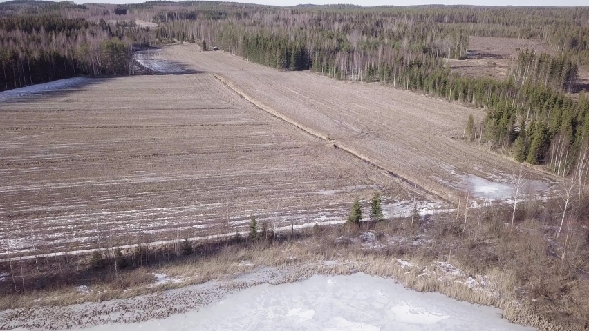 Melting plowed field at lakeside in springtime. Aerial shot.
