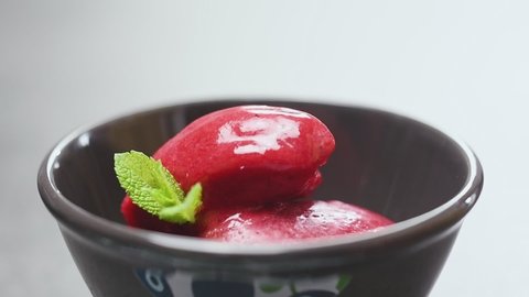Scooping raspberry sorbet with a spoon.