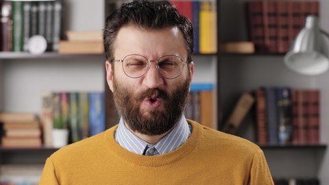 Man disgust, abomination, FU, auch emotion. Bearded male teacher or businessman with glasses looking at camera and his face is distorted in disgust. Slow motion