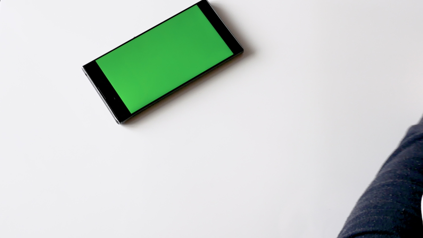 A man uses a smartphone with a green display. Swipe your finger across the chromatic key smart phone screen or green screen smart phone to copy space