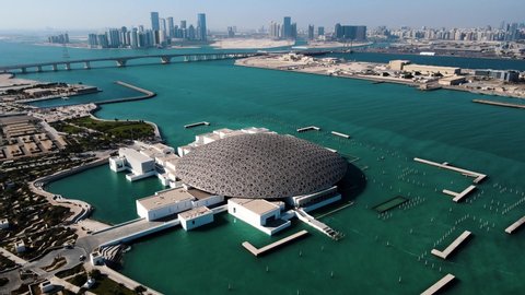 Abu Dhabi, United Arab Emirates - April 6, 2021: Louvre museum in Abu Dhabi emirate of the United Arab Emirates at sunrise aerial drone footage of the building appear to float on the seaside