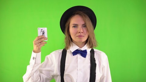 Croupier Woman in a White Shirt and Hat Shows Playing Cards, Smiling and Winks an Eye. Joker Cards. Greenscreen, Studio, Chroma Key