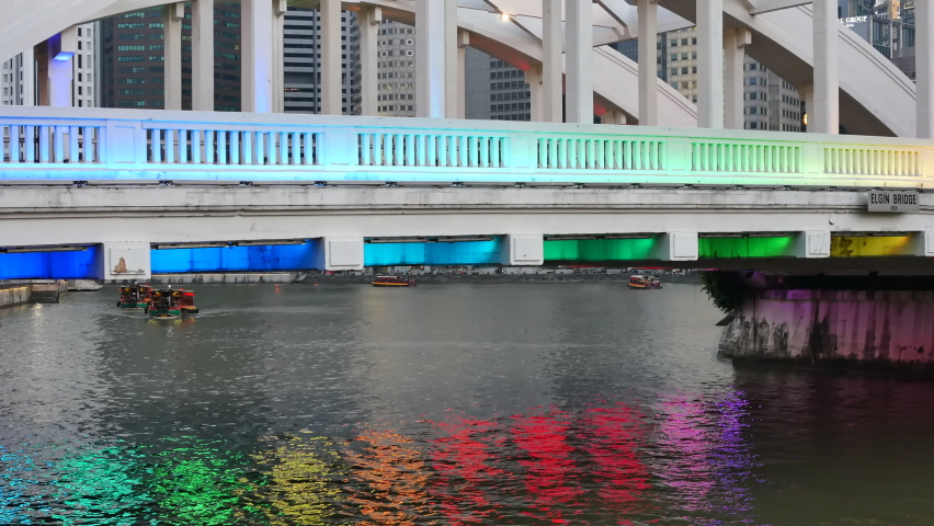 SINGAPORE - FEBRUARY 11, 2018: Tourist boats under the colorful bridge in Signapore. Handheld.