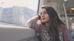 A close shot of a beautiful Indian young stressed woman solo traveler in a traditional salwar kurta sitting in a moving metro train leaning on a window and looking outside. Mental health concept  - Powered by Shutterstock - Get 15% off with code: PIKWIZARD15