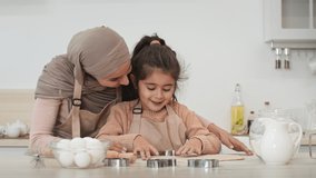 Young Muslim Mother In Hijab And Little Daughter Making Cookies With Baking Forms In Modern Kitchen At Home. Arabic Mom And Her Kid Girl Bonding Cooking Together