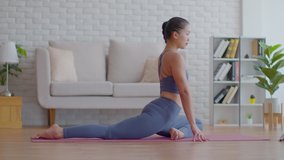 Attractive Asian woman practice yoga king pigeon pose online course at home to meditation comfortable and relax,Health care and Exercise at home Concept,Self-isolation due COVID-19 pandemic