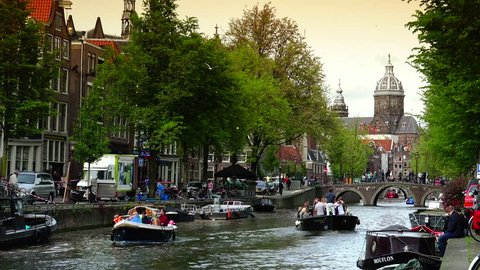 AMSTERDAM, NETHERLANDS - MAY 19: Canal and St. Nicolas Church in Amsterdam. Amsterdam is the capital and most populous city of the Netherlands on MAY 19, 2015; ULTRA HD 4K, real time