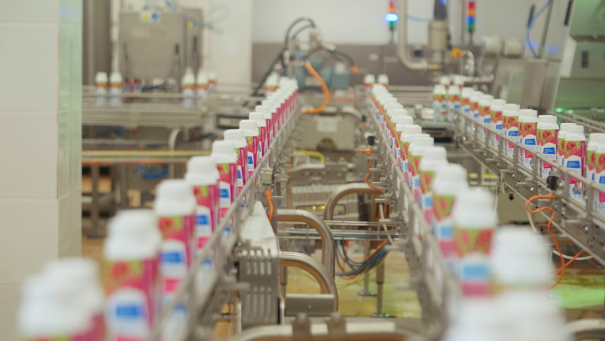 Packages with yogurt Traveling Along a Conveyor belt. Production of Dairy Based Products. Yogurt Making. Automated Process. Manufacturing Line. Modern Processing of Milk. Packaging. Inside a Factory Royalty-Free Stock Footage #1071076135