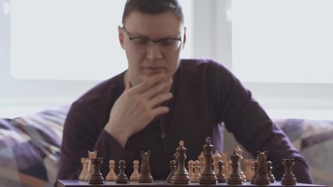 chess player performs a move with chess pieces on a wooden board. The player plays chess on his own in a pandemic. The trainer of chess tactics with himself