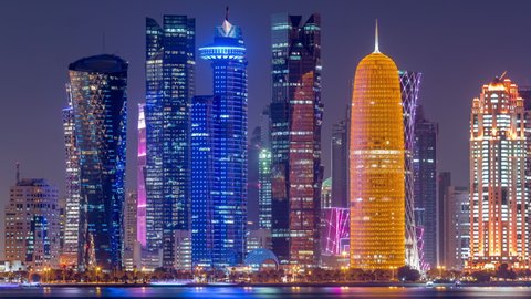 Doha downtown skyline day to night transition timelapse, Qatar, Middle East. Illuminated skyscrapers on a West Bay reflected in a water of Gulf. Close up view