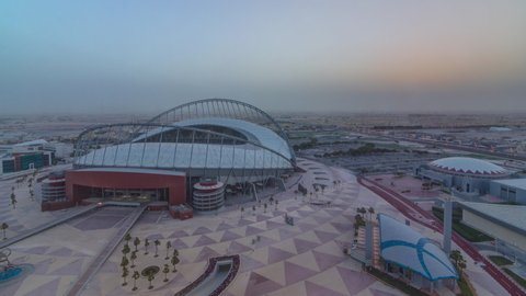 Aerial view of Aspire Zone from top at sunrise timelapse in Doha. Traffic on the road and car parking. Foggy weather